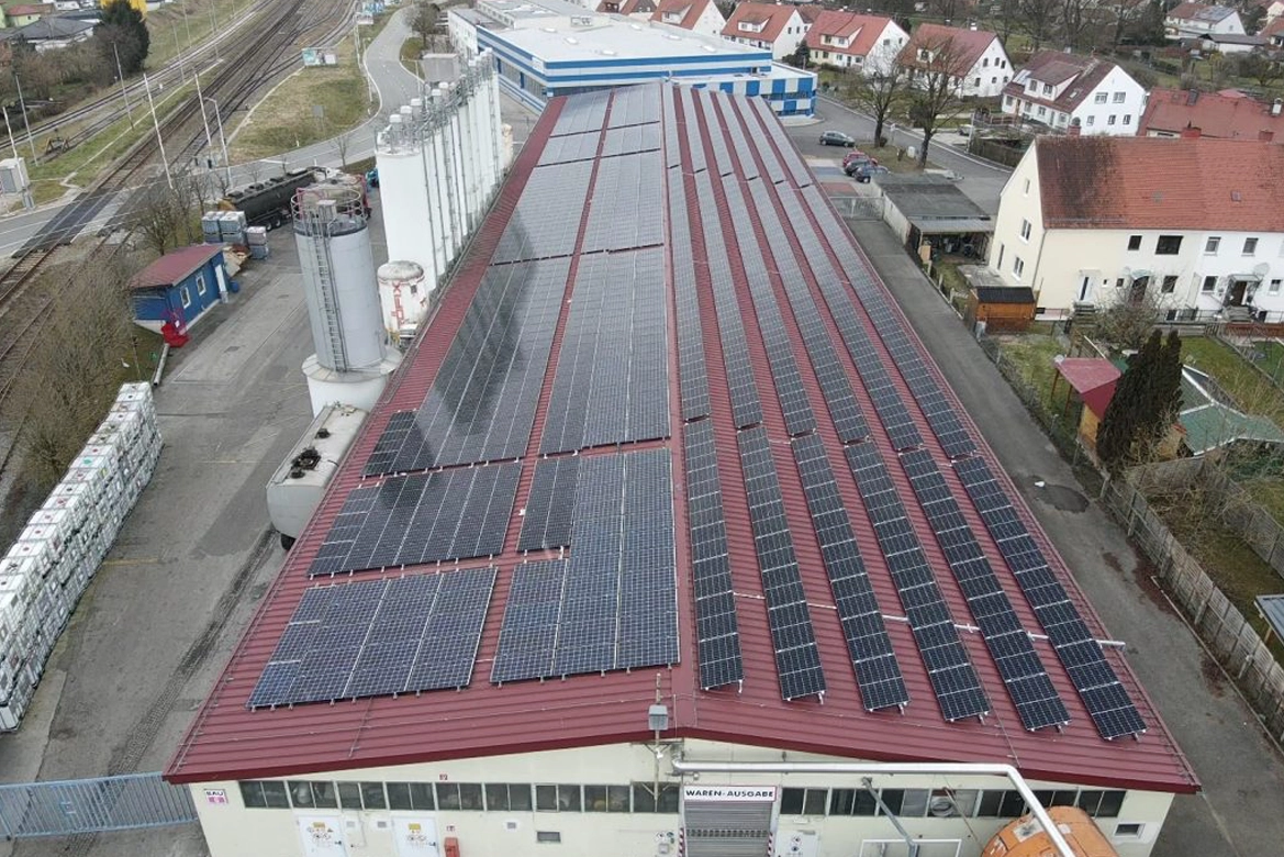 Dach mit Photovoltaikanlagen, die Sonnenenergie zur Stromerzeugung nutzen, auf einem Gebäude in einer städtischen Umgebung.